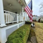 A picture of a USA flag fixed on the front lawn of the house